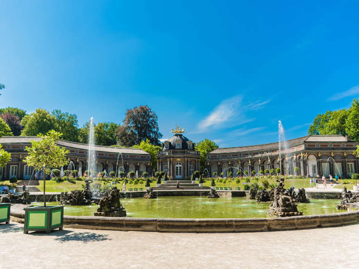 Wasserbecken mit Fontänen, dahinter neues Schloss mit Sonnentempel